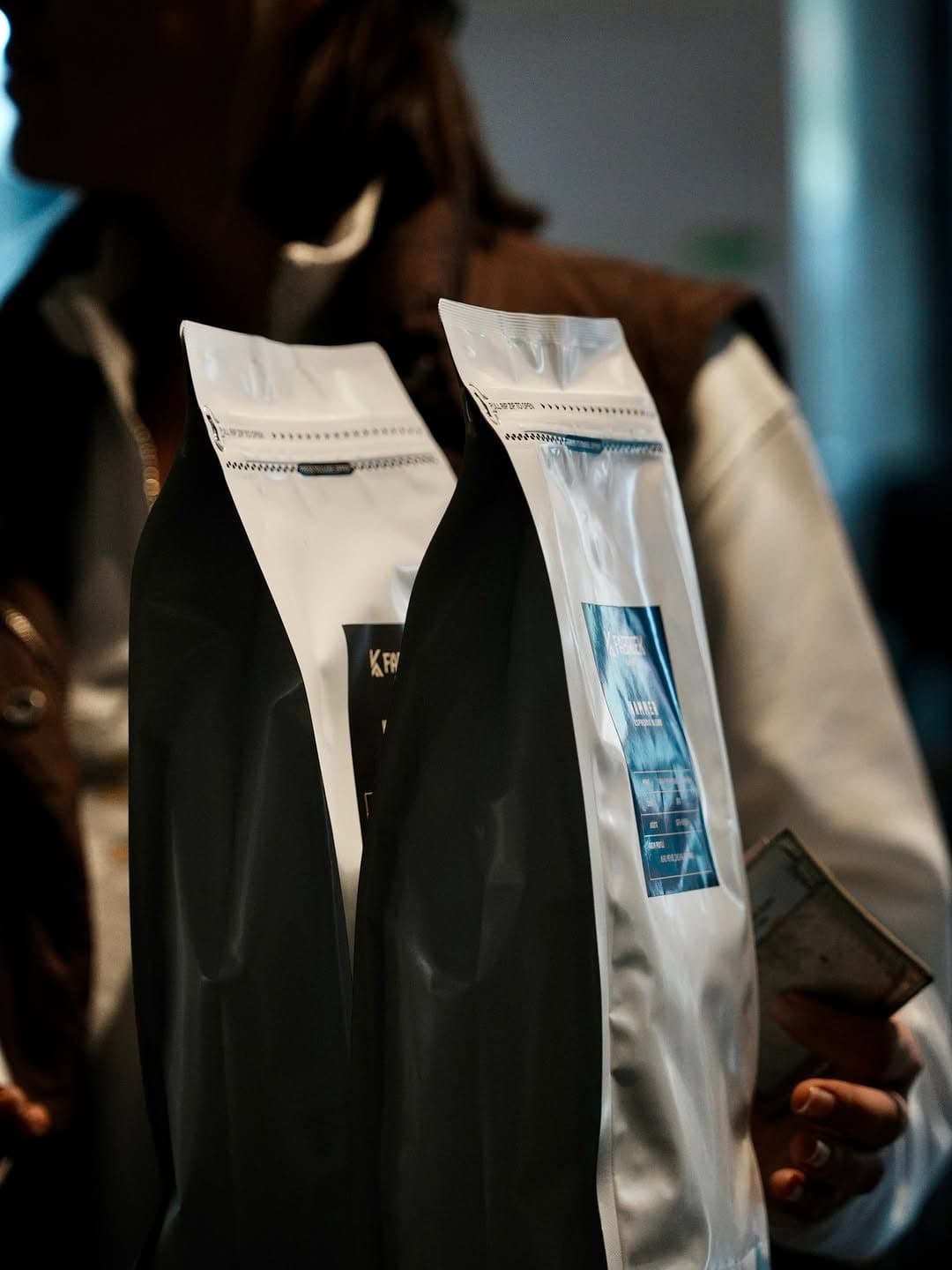 Black and silver coffee bags held in front of a person