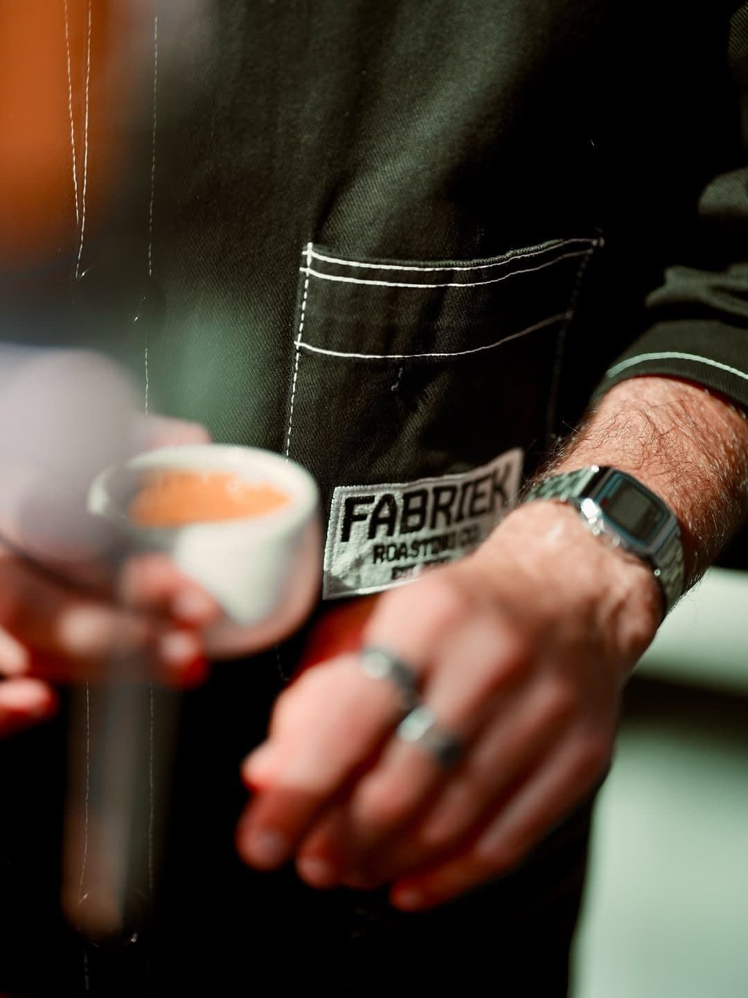Black apron with a FABRIEK Roasting Co. pocket and an espresso cup in hand